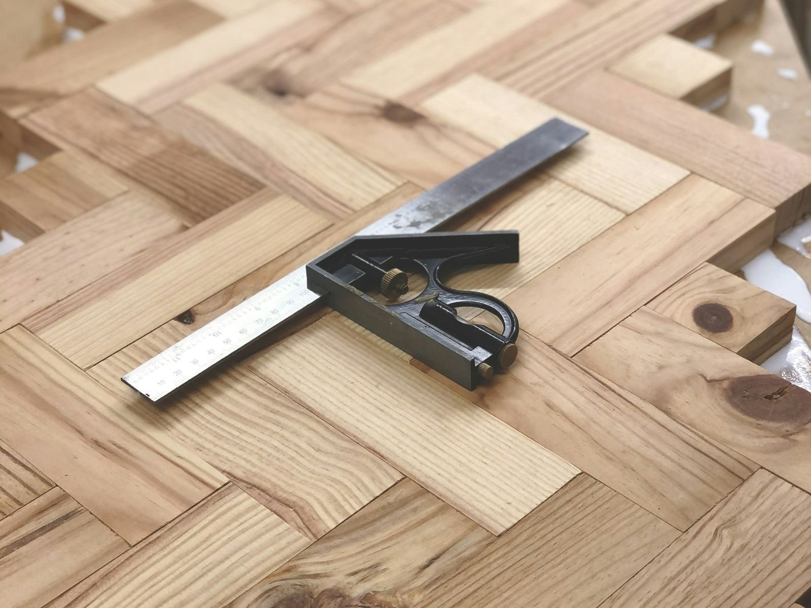 Pose d'un parquet en bâton rompu, équerre posée sur les lames