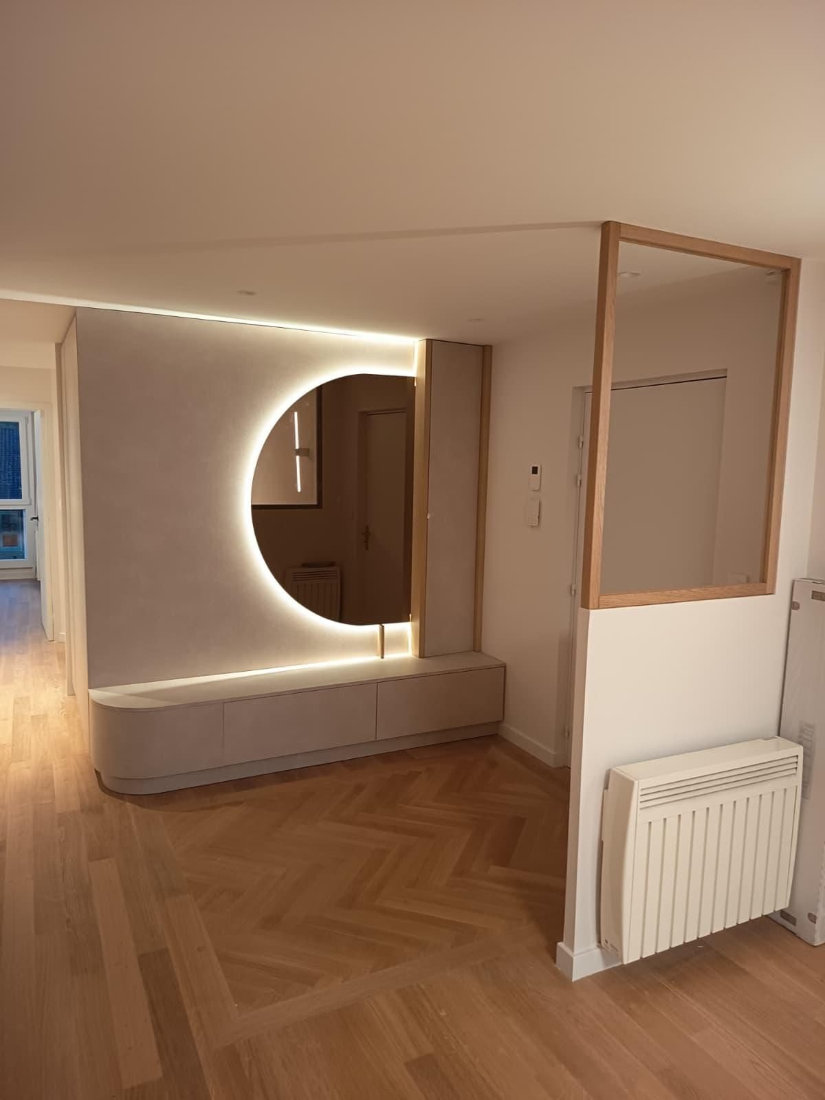 Entrée au parquet en chêne avec un panneau en bâton rompu devant un miroir éclairé