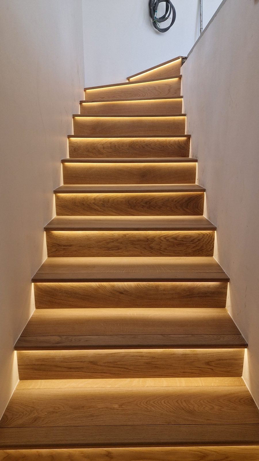 Escalier droit aux marches et contremarches en chêne, souligné de rubans lumineux
