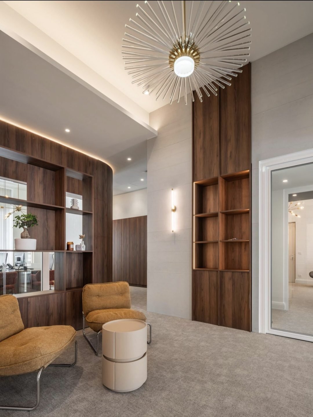 Espace d'accueil avec fauteuils et rangements en noyer, sol en moquette grise